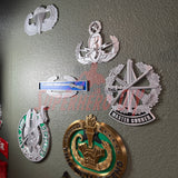 Master Gunner Badge display insignia showcased alongside other military badges on a wall.