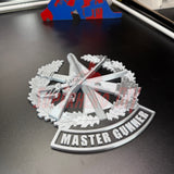 Master Gunner Badge display insignia in 3D on a dark surface with detailed design elements.