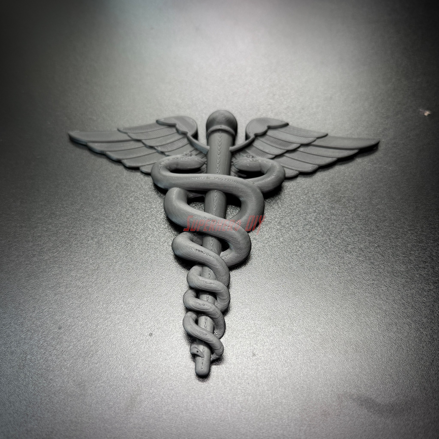 Army Medical Corps caduceus wall display in black, featuring twin serpents and wings on a dark background.