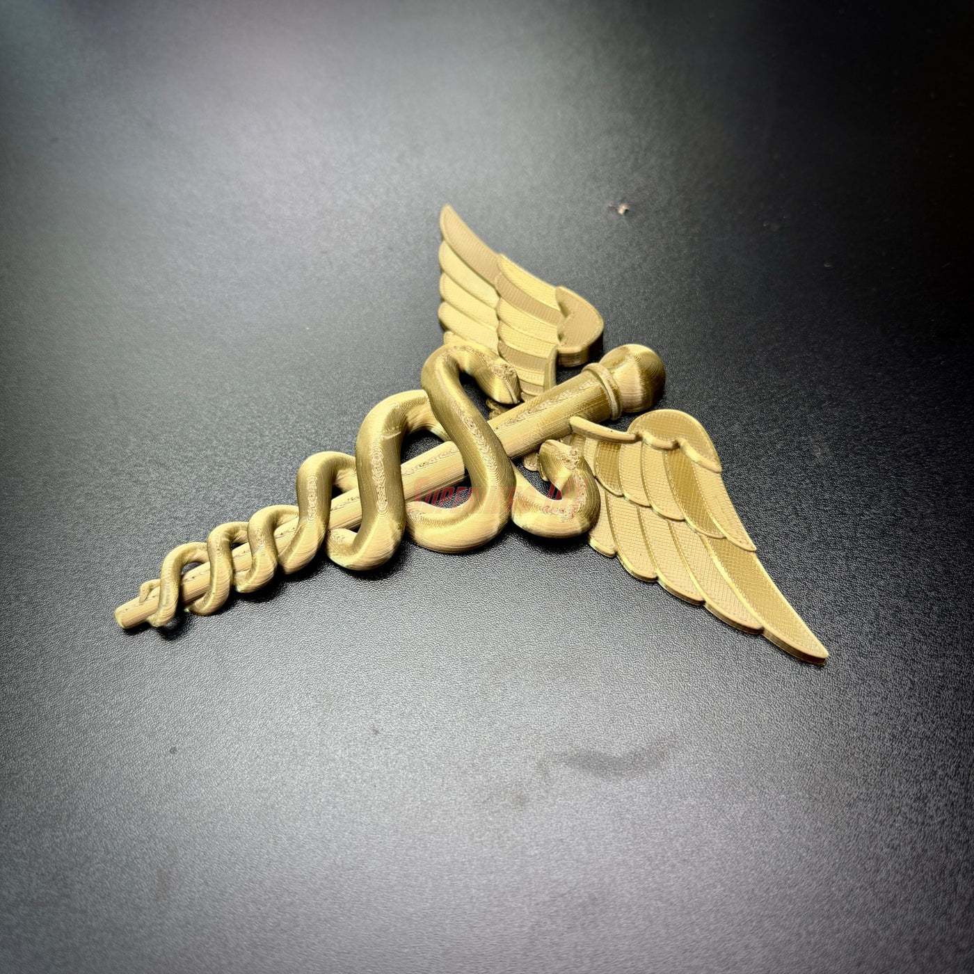 army medical corps caduceus wall display in gold color with wings and serpents on a dark surface
