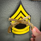 Army military police insignia featuring gold crossed pistols on a black and yellow wall display.