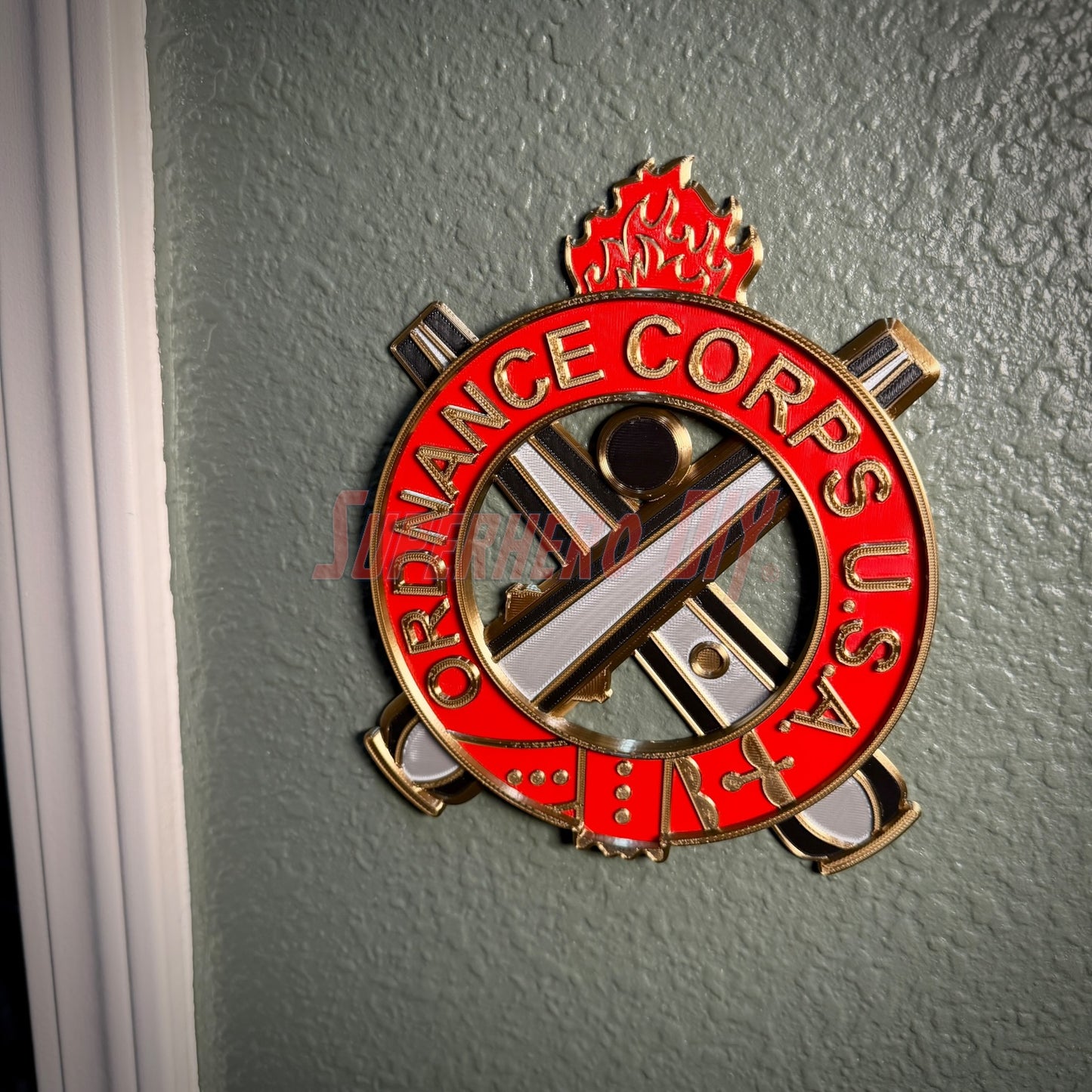 Ordnance Regimental Crest displayed on a wall, representing the Ordnance Corps, USA with red and gold colors.