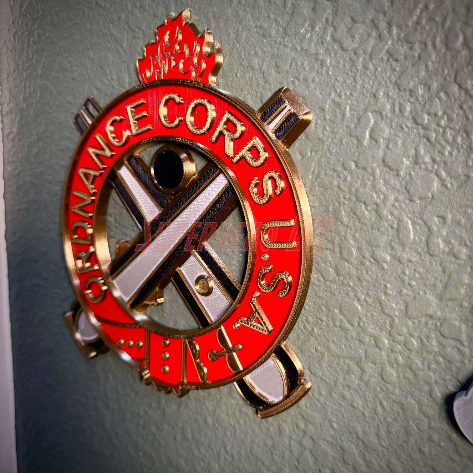 Ordnance Regimental Crest displayed on a wall, showcasing red and gold colors of the Ordnance Corps USA.