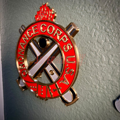 Ordnance Regimental Crest displayed on a wall, showcasing red and gold colors of the Ordnance Corps USA.