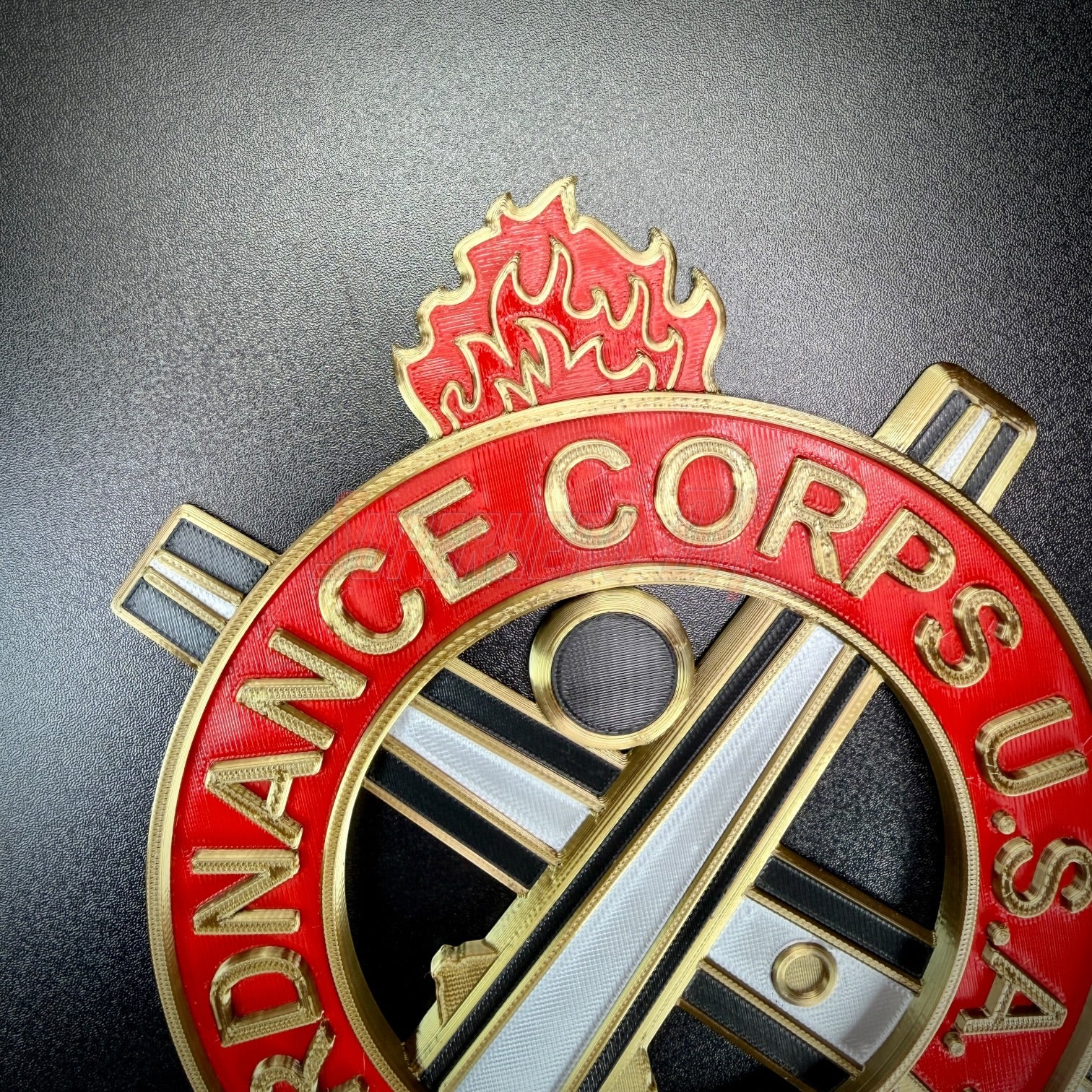 Ordnance regimental crest featuring flame emblem and crossed tools, representing the Ordnance Corps.
