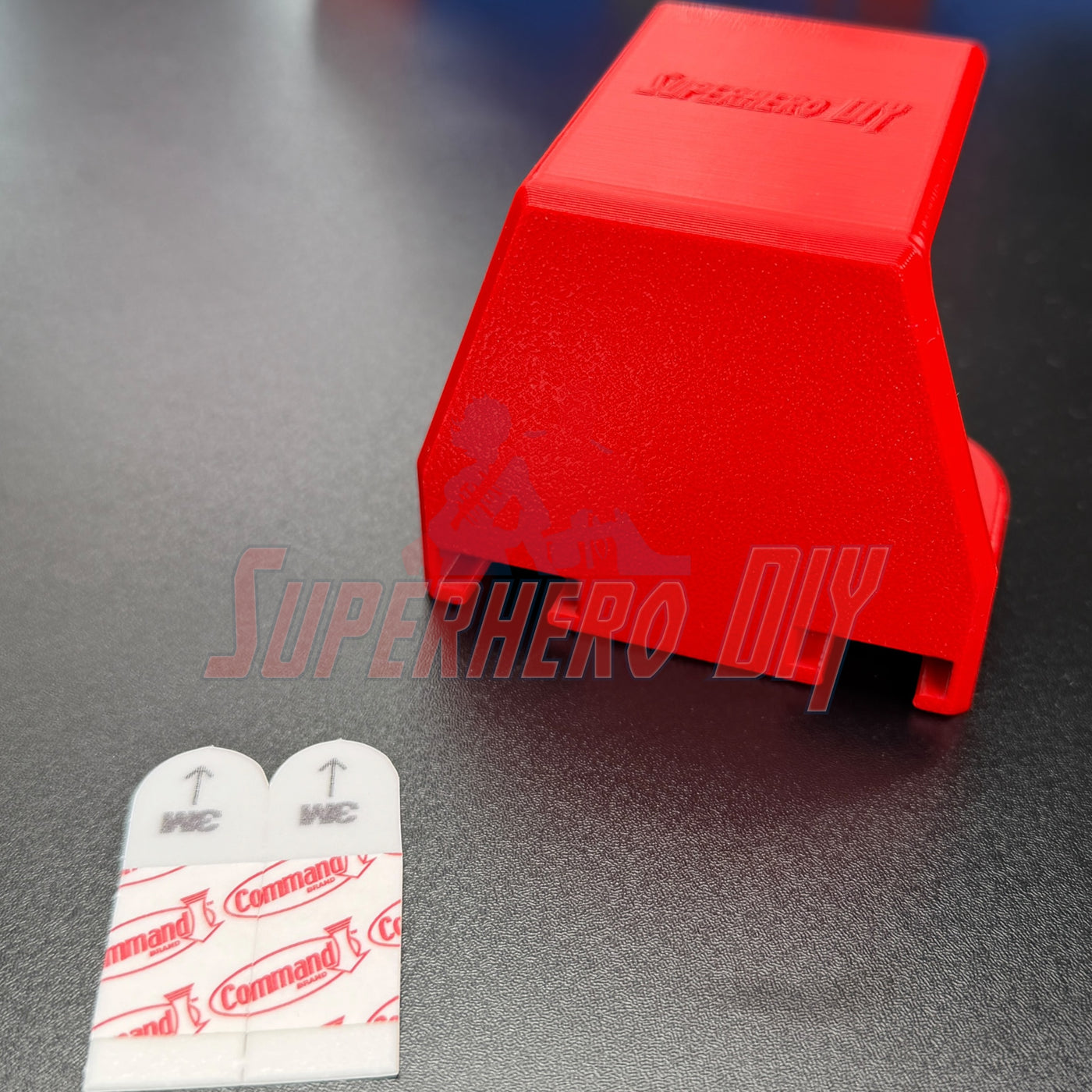 Under-desk PS5 controller mount in red with Command adhesive strips for easy installation.