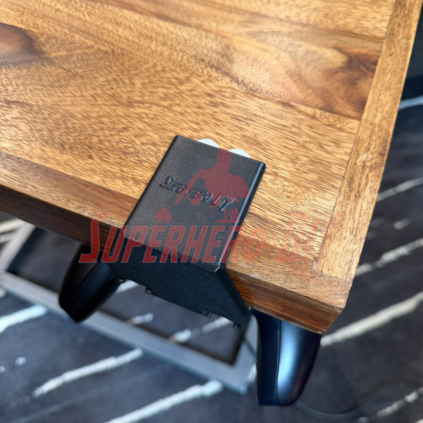 Under-desk PS5 controller mount attached to a wooden desk, securely holding the controller underneath.