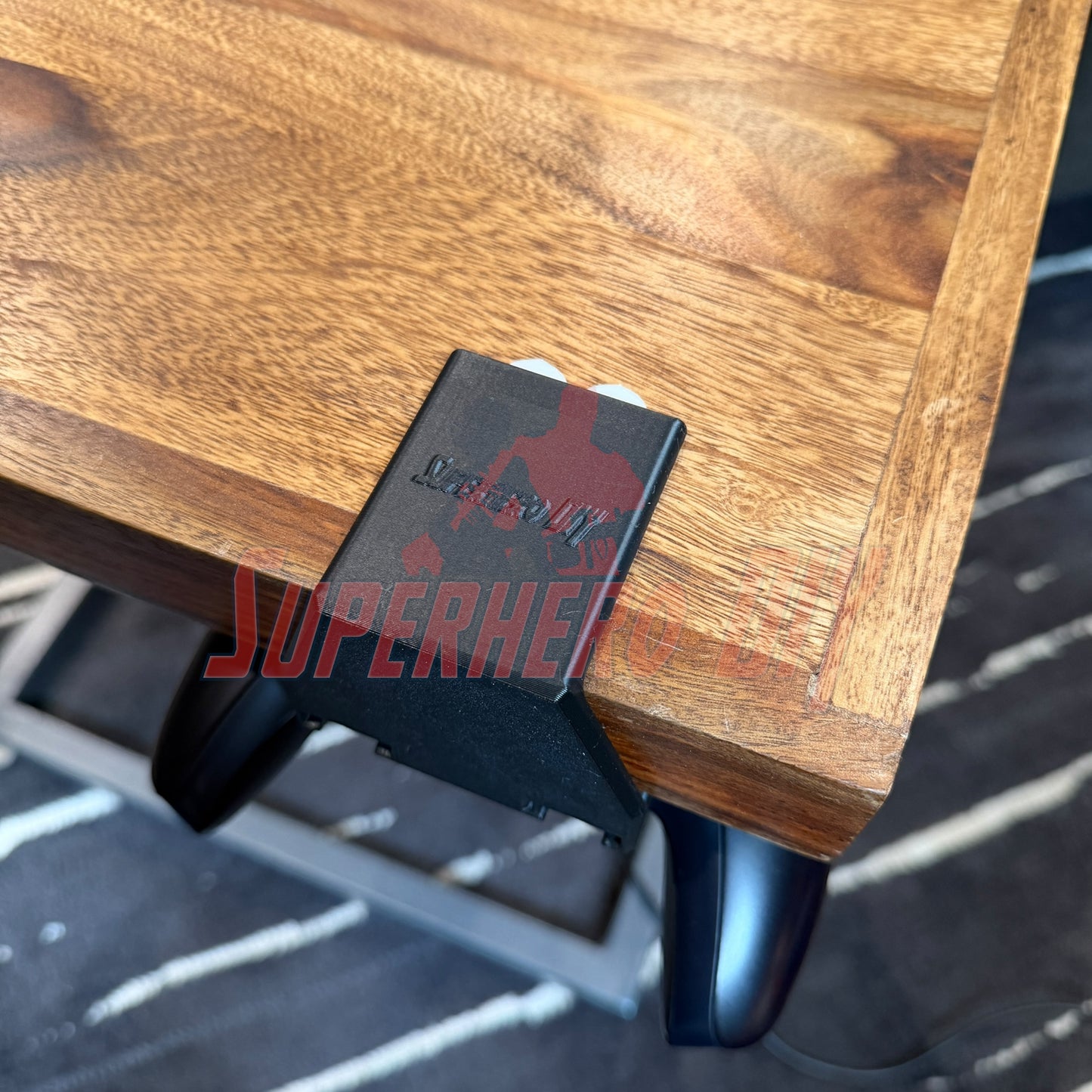 Under-desk PS5 controller mount attached to a wooden desk, securely holding the controller underneath.