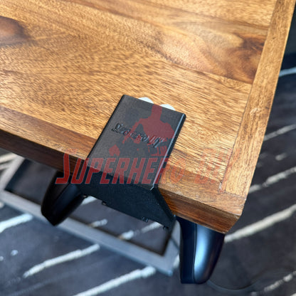 Under-desk PS5 controller mount attached to a wooden desk, securely holding the controller underneath.