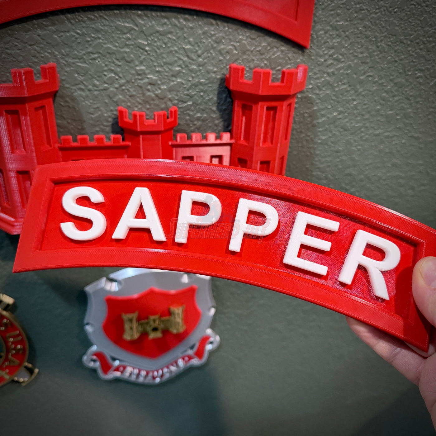 3D sapper tab display piece with red background and white lettering showcasing 'SAPPER' for combat engineers.