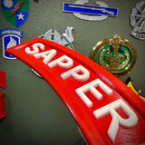 3D sapper tab display piece showcasing the word SAPPER in raised white letters on a red background.