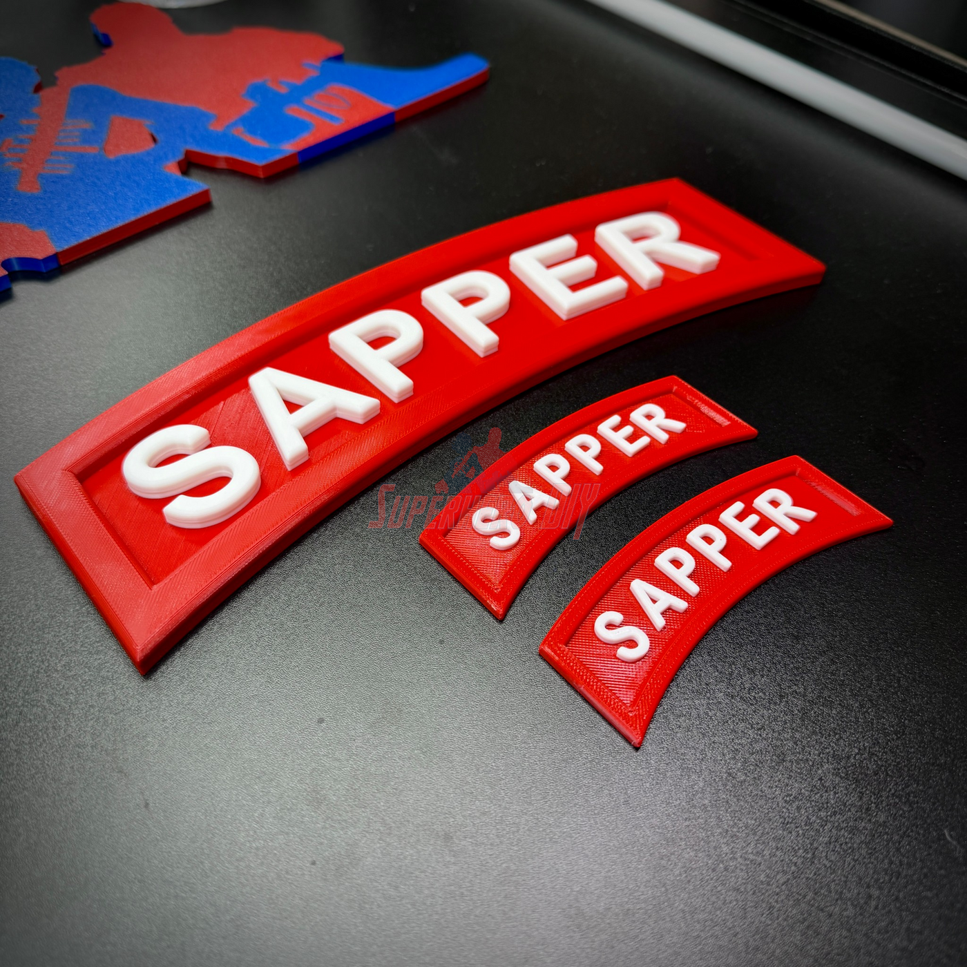 3D sapper tab display featuring multiple sizes of SAPPER tabs in red and white.