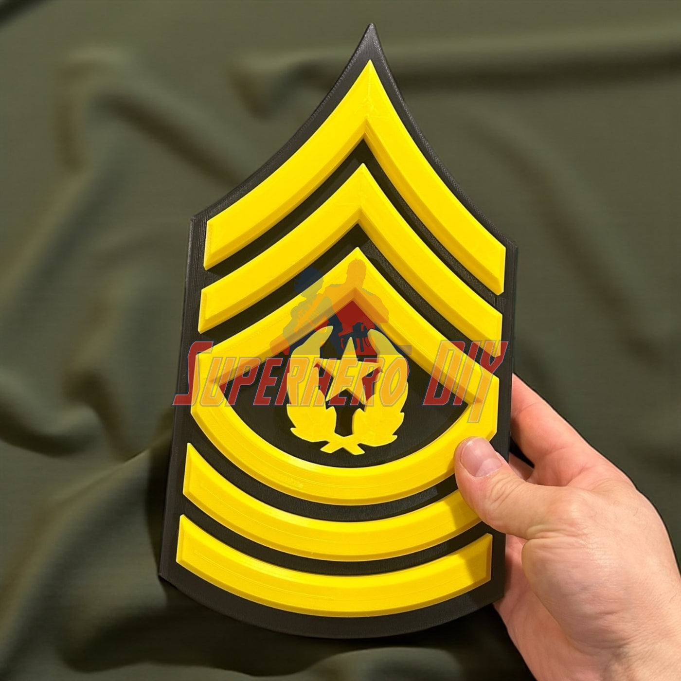 3D-printed Army enlisted rank insignia in hand, showcasing a sergeant's rank with bold yellow details.