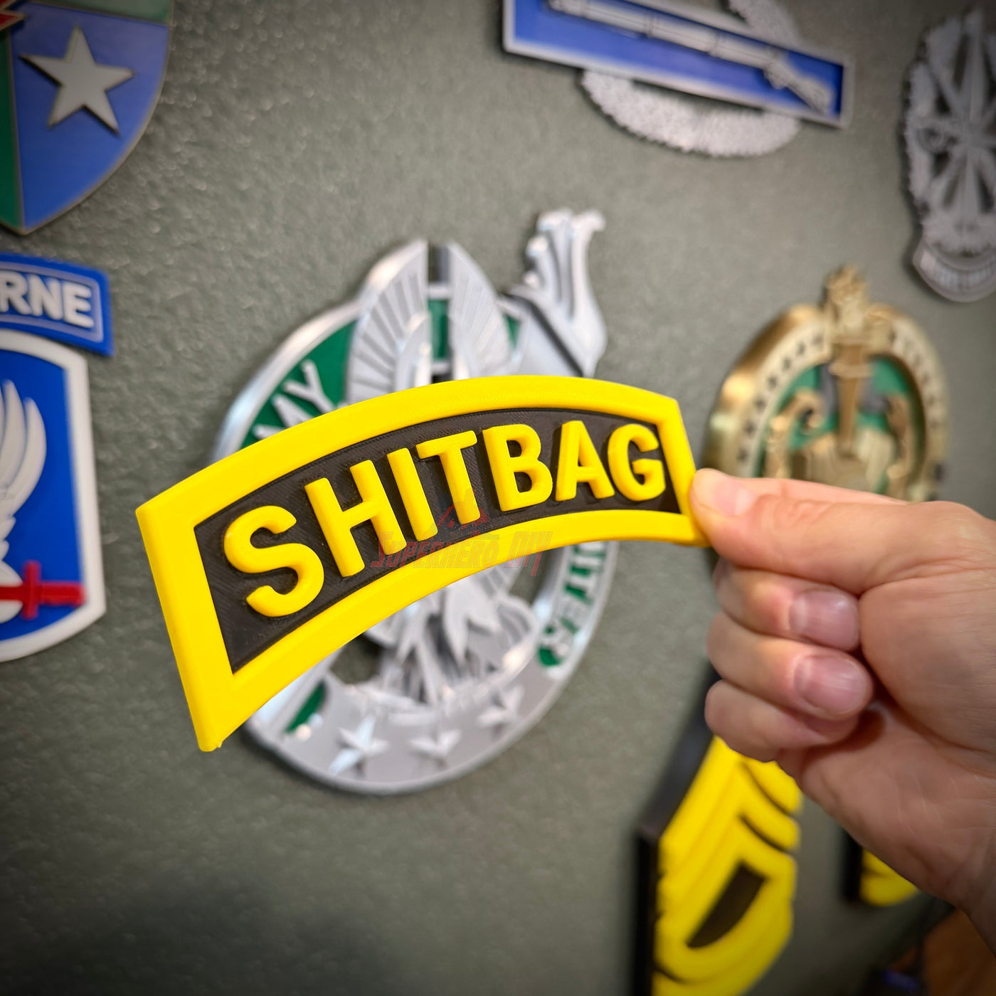 Person holding a SHITBAG tab in yellow and black, perfect gag gift for military friends.