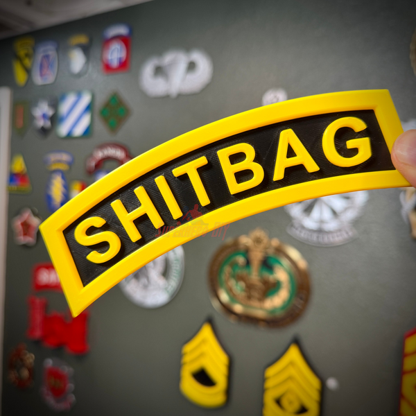 Close-up of a SHITBAG tab in black and yellow, showcasing a humorous gag gift for soldiers.
