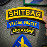 Image of SHITBAG tab along with Special Forces and Airborne patches on a wall display.