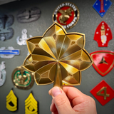 O-4 Major Navy lieutenant commander rank insignia in gold silk finish held by hand.