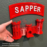 Person holding a red wall-mountable Army Engineer Castle display with 'SAPPER' sign, designed for easy wall-mounting.