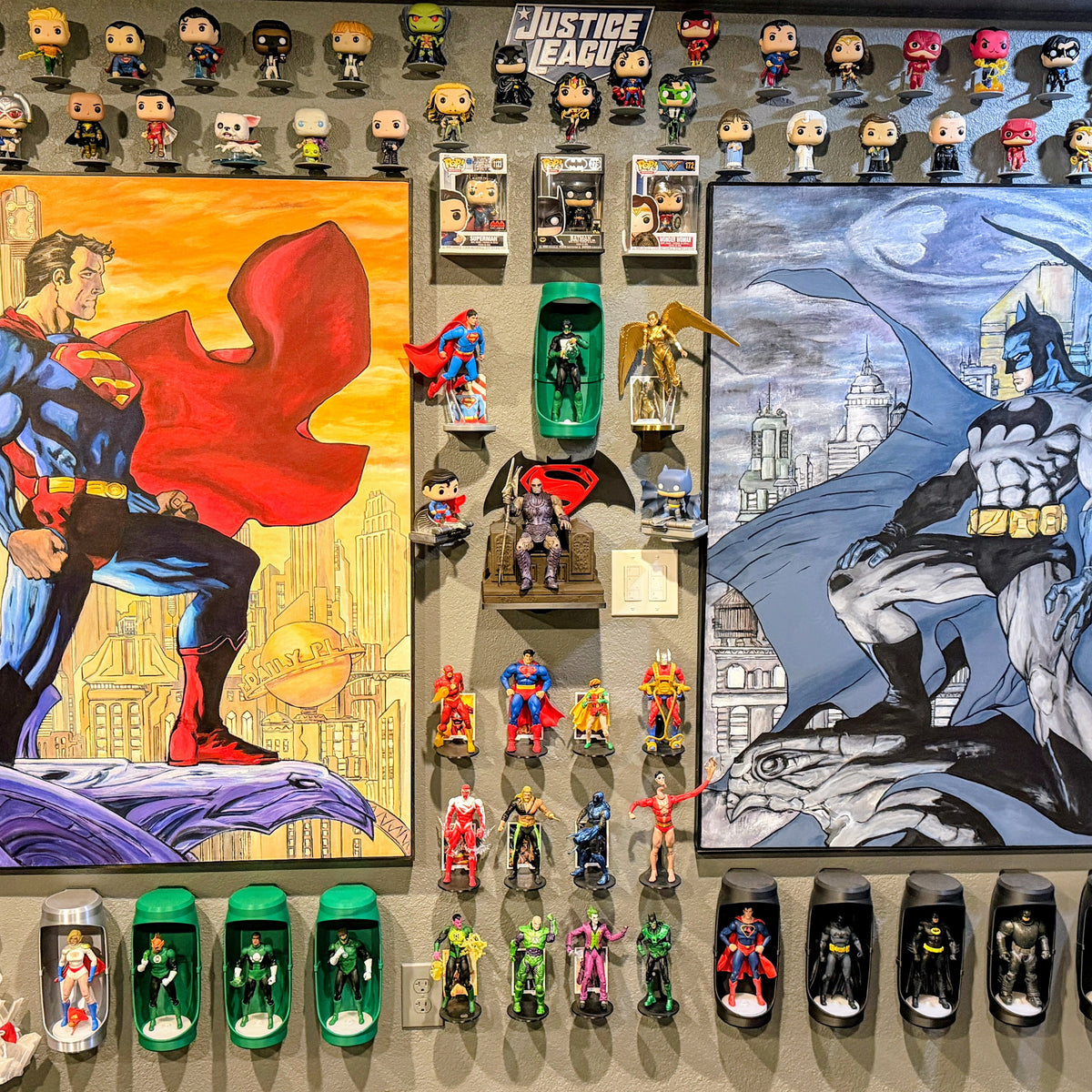 Collection of superhero action figures and artwork on a wall.