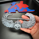 Subdued air assault badge in hand, showcasing detailed wings and military insignia.