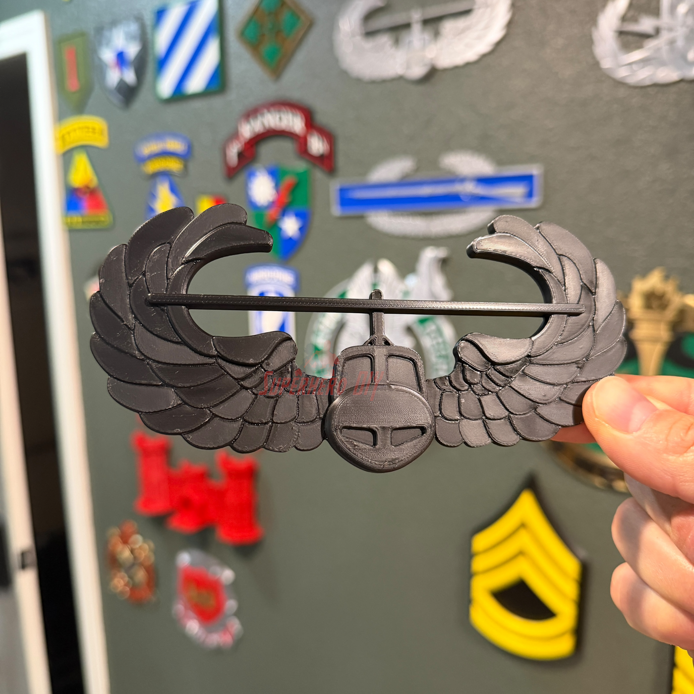 Air Assault Badge display insignia in black finish held in hand, showcasing military heritage.