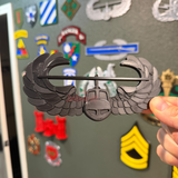 Air Assault Badge display insignia in black finish held in hand, showcasing military heritage.