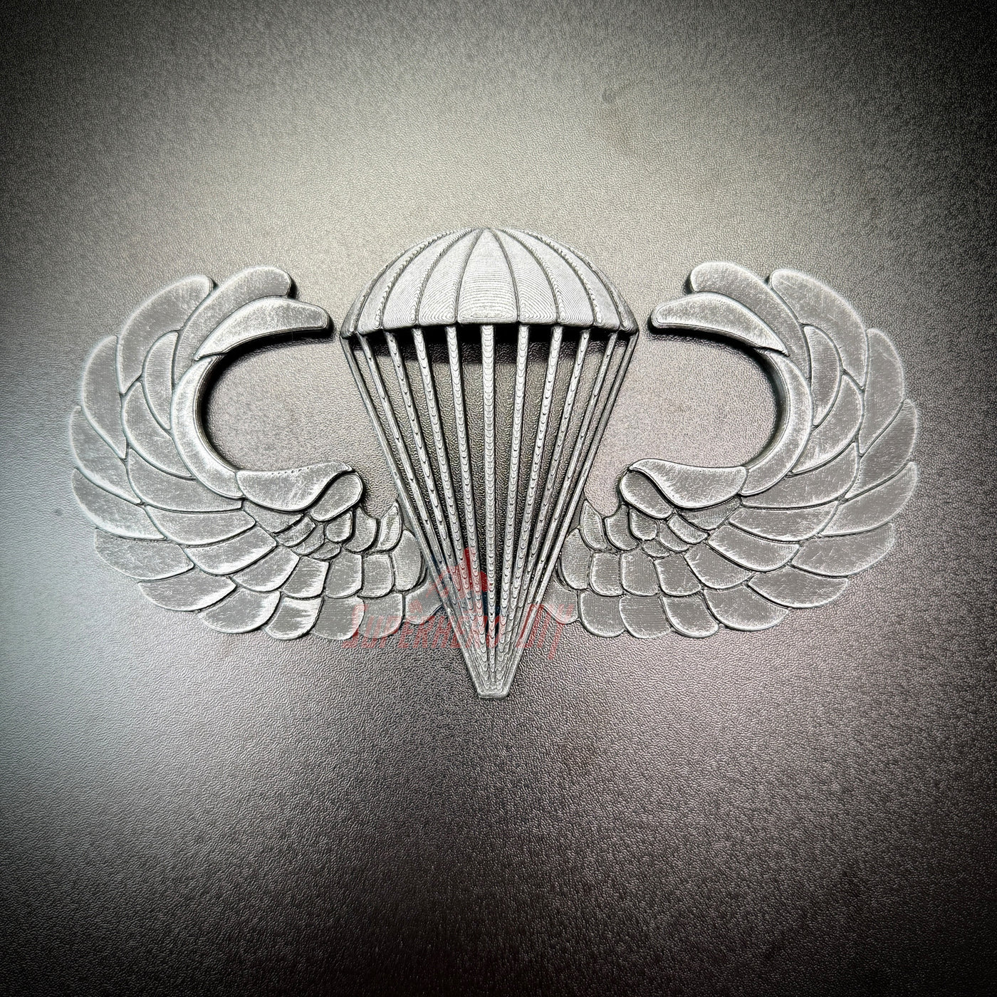 Subdued airborne jump wings badge featuring iconic parachute and wings design.