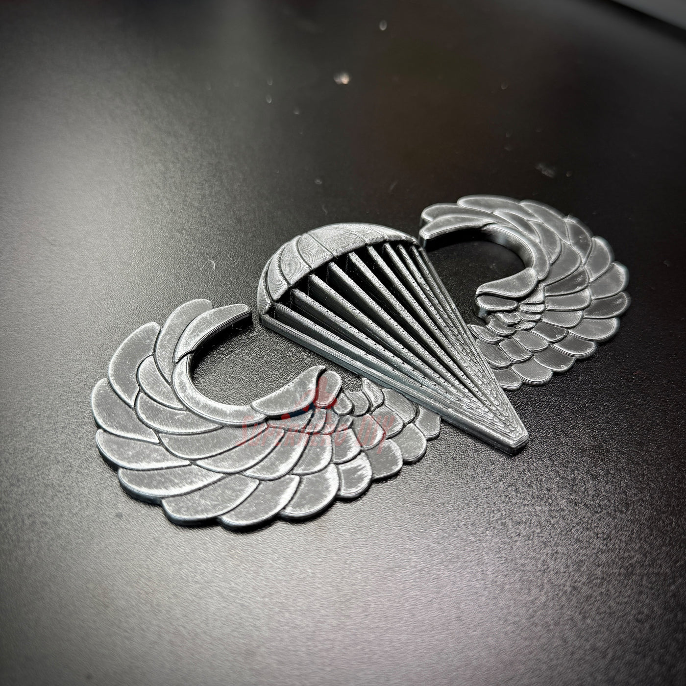 Subdued Airborne Jump Wings on a black background, showcasing the intricate design of the Parachutist Badge.