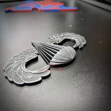 Subdued airborne jump wings badge displayed on a black background, showcasing intricate details and design.