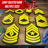 Army enlisted rank insignia displayed in multiple sizes on wooden background, showcasing various ranks with a bold design.