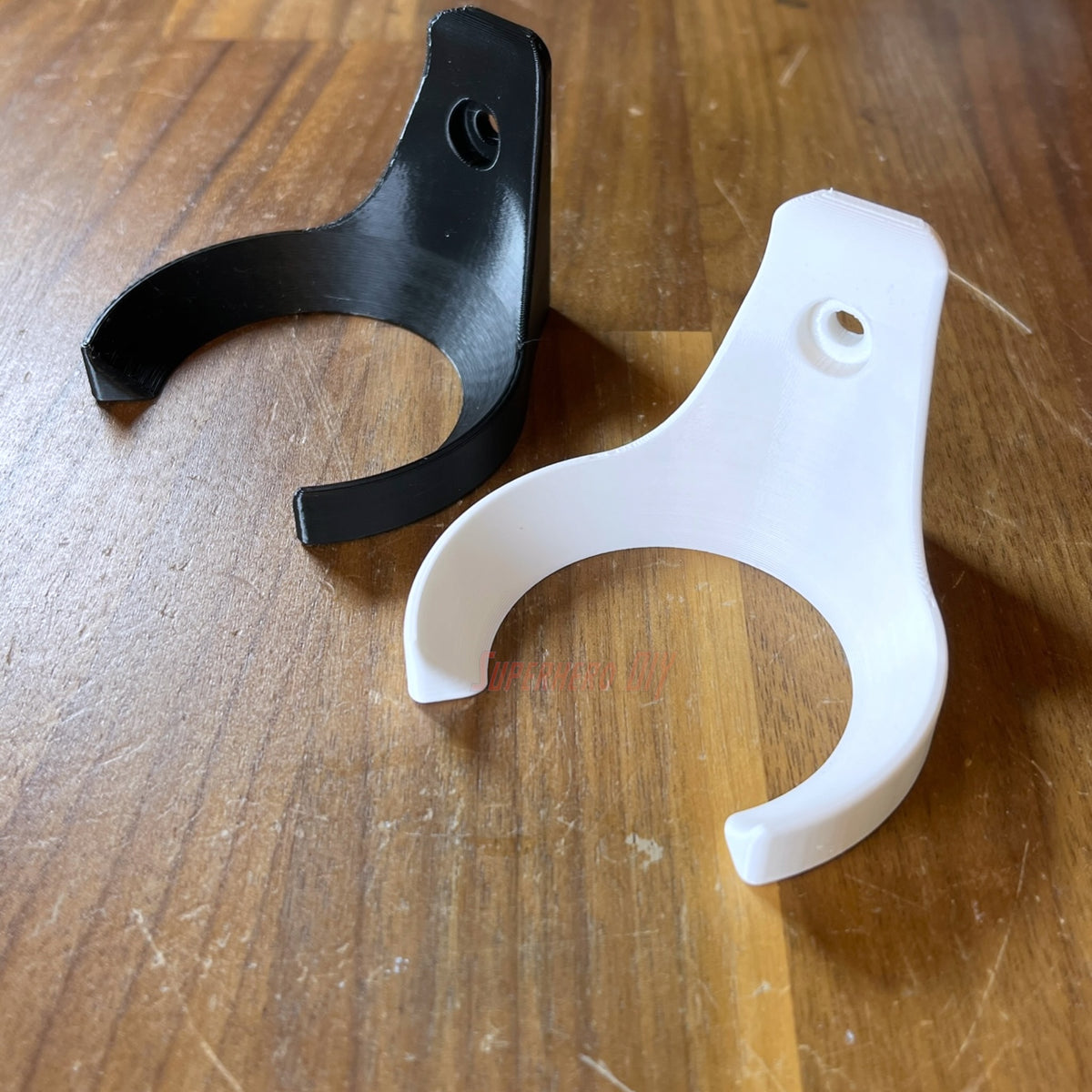Black and white baseball wall mount holders lying on a wood table, empty