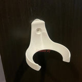 Empty white baseball holder wall mount on a dark wall, screw hole visible