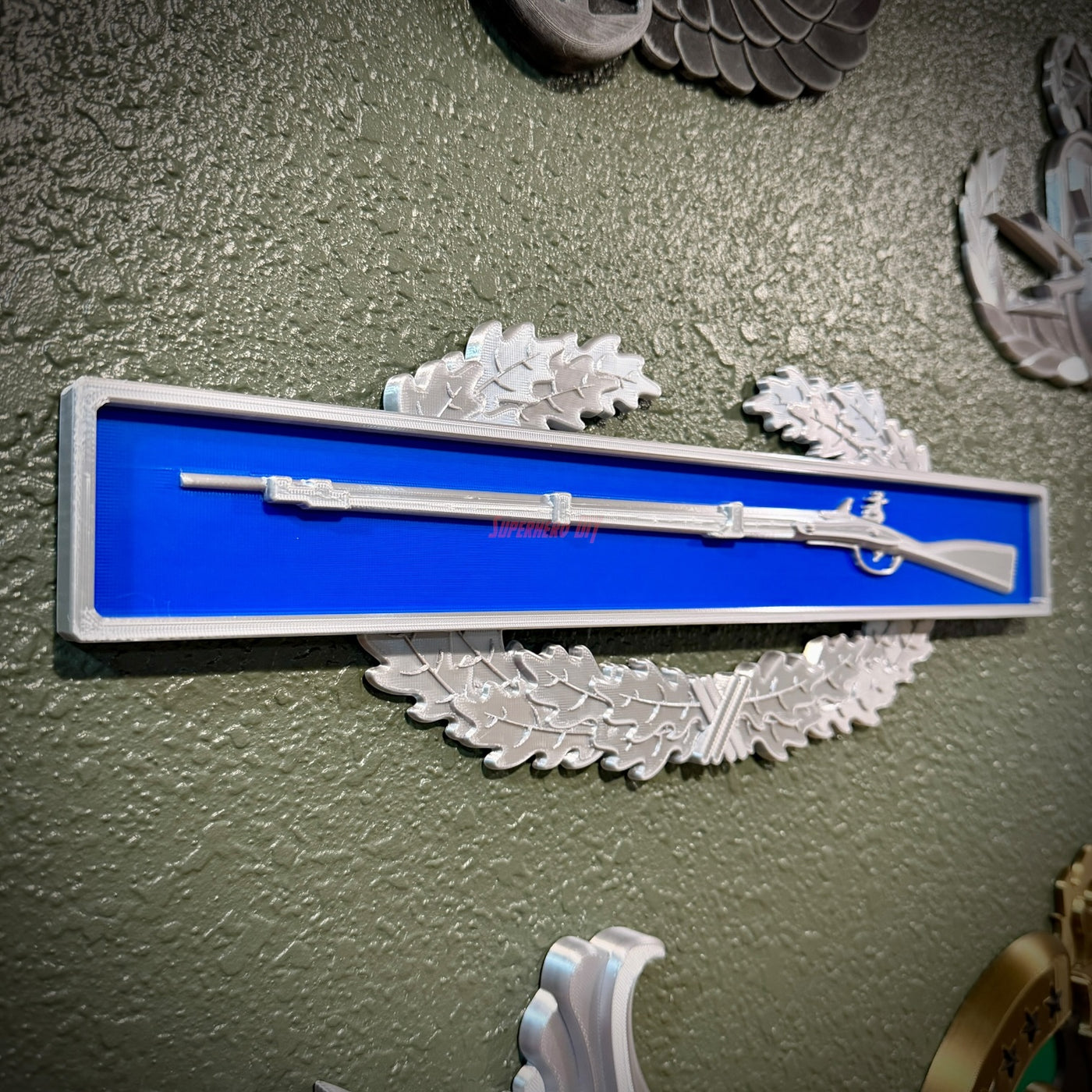 Infantryman Badge replica displaying a silver musket on a blue background, showcasing combat infantryman badge insignia.