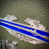 Close-up of Infantryman Badge replica with oak leaves and blue bar, featuring 1795 Springfield musket.