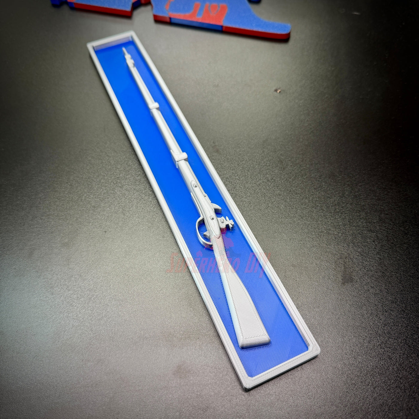 3D-printed Expert Infantryman Badge replica with a white rifle design on a blue background.