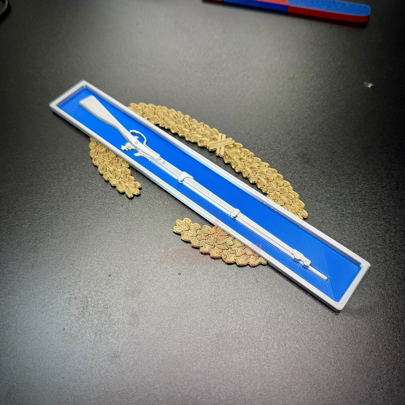Master Combat Infantryman Badge displayed on a blue background with gold insignia, representing military achievement.