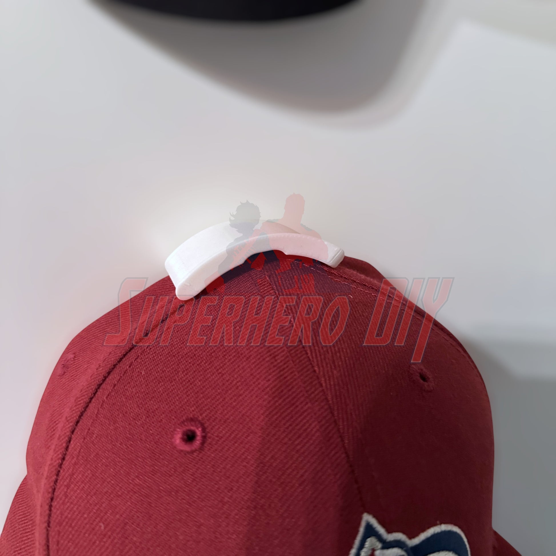 Hat display wall mount showcasing a maroon cap, ideal for organizing and displaying hats without wall damage.
