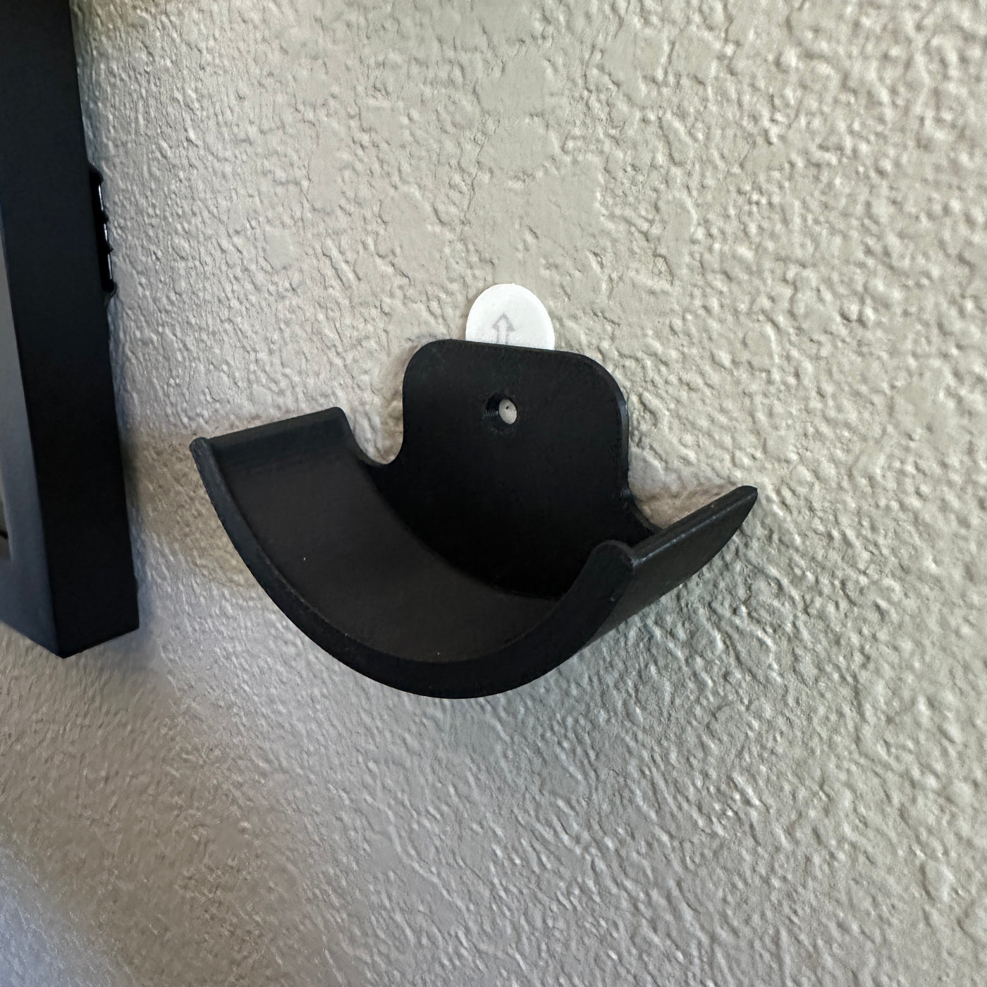 Close-up of a black hockey puck holder wall mount showcasing its curved design for displaying hockey pucks.