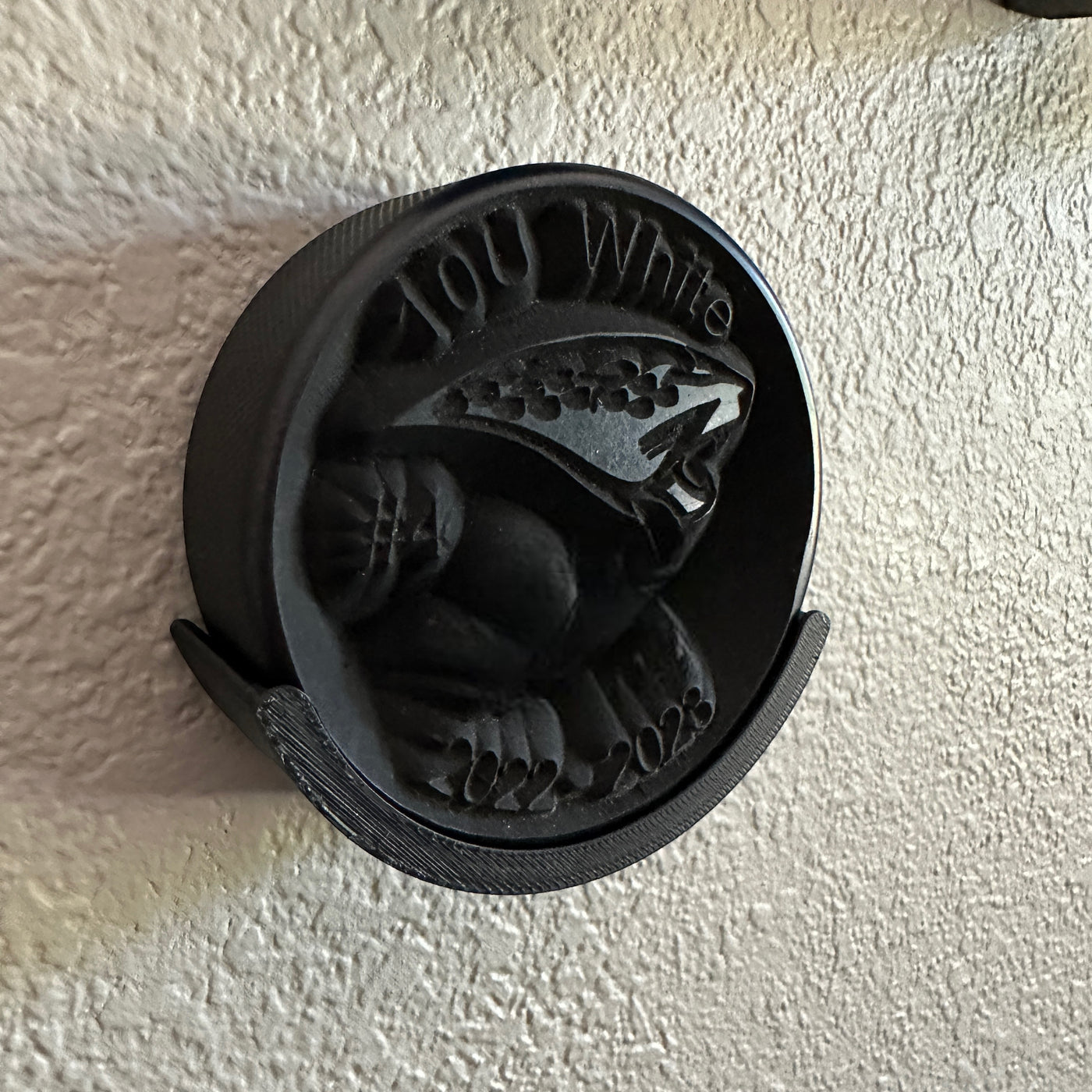 Detailed view of a 3D-printed hockey puck holder wall mount, showcasing a unique design and black finish.