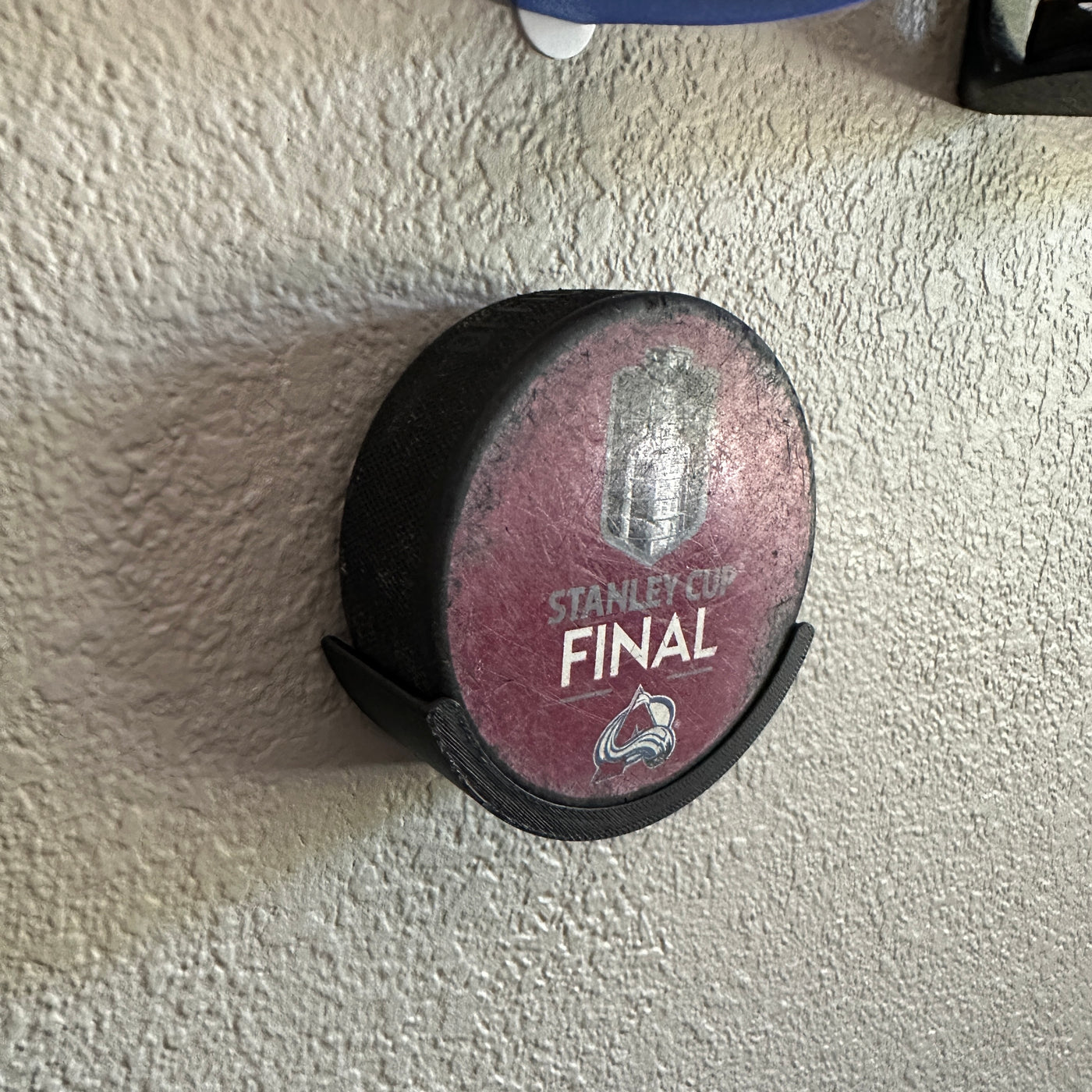 Hockey puck holder showcasing a Stanley Cup Final puck mounted on a wall.