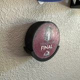 Hockey puck holder showcasing a Stanley Cup Final puck mounted on a wall.
