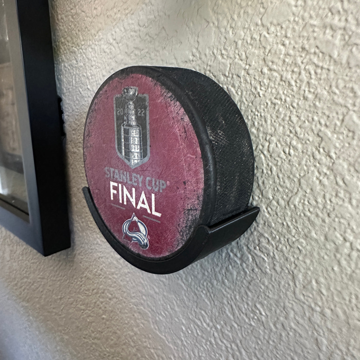 Hockey puck holder displaying a Stanley Cup Final 2022 puck on a wall, perfect for hockey enthusiasts.