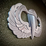 Parachutist jump wings badge displayed on a textured green wall, representing military airborne achievement.