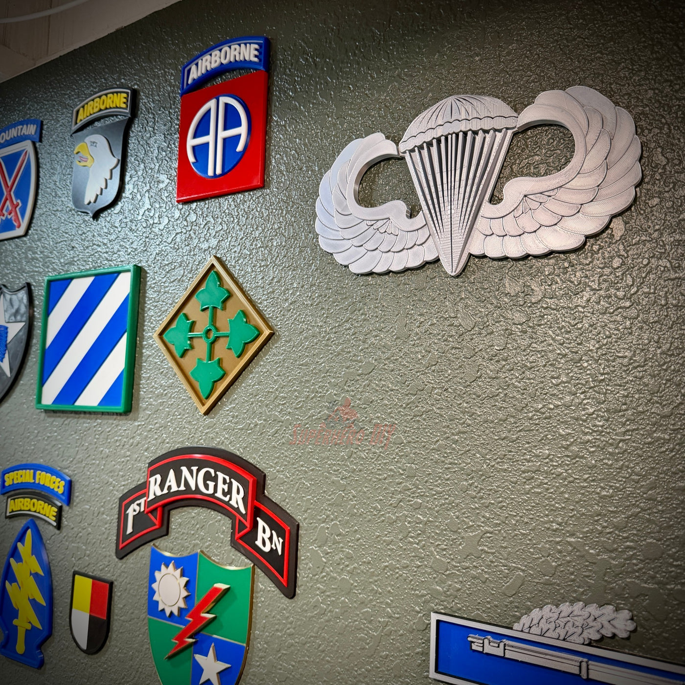 parachutist jump wings badge displayed on a wall with other military insignia and patches