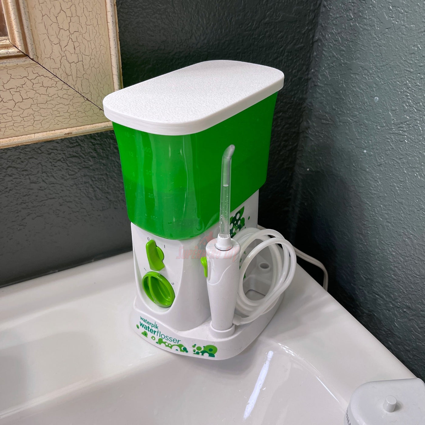 Lid for Waterpik Traveler Water Flosser WP-300 in green and white on bathroom counter protecting water tank.