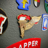 Army Pathfinder Badge display insignia on wall with various military patches in background.