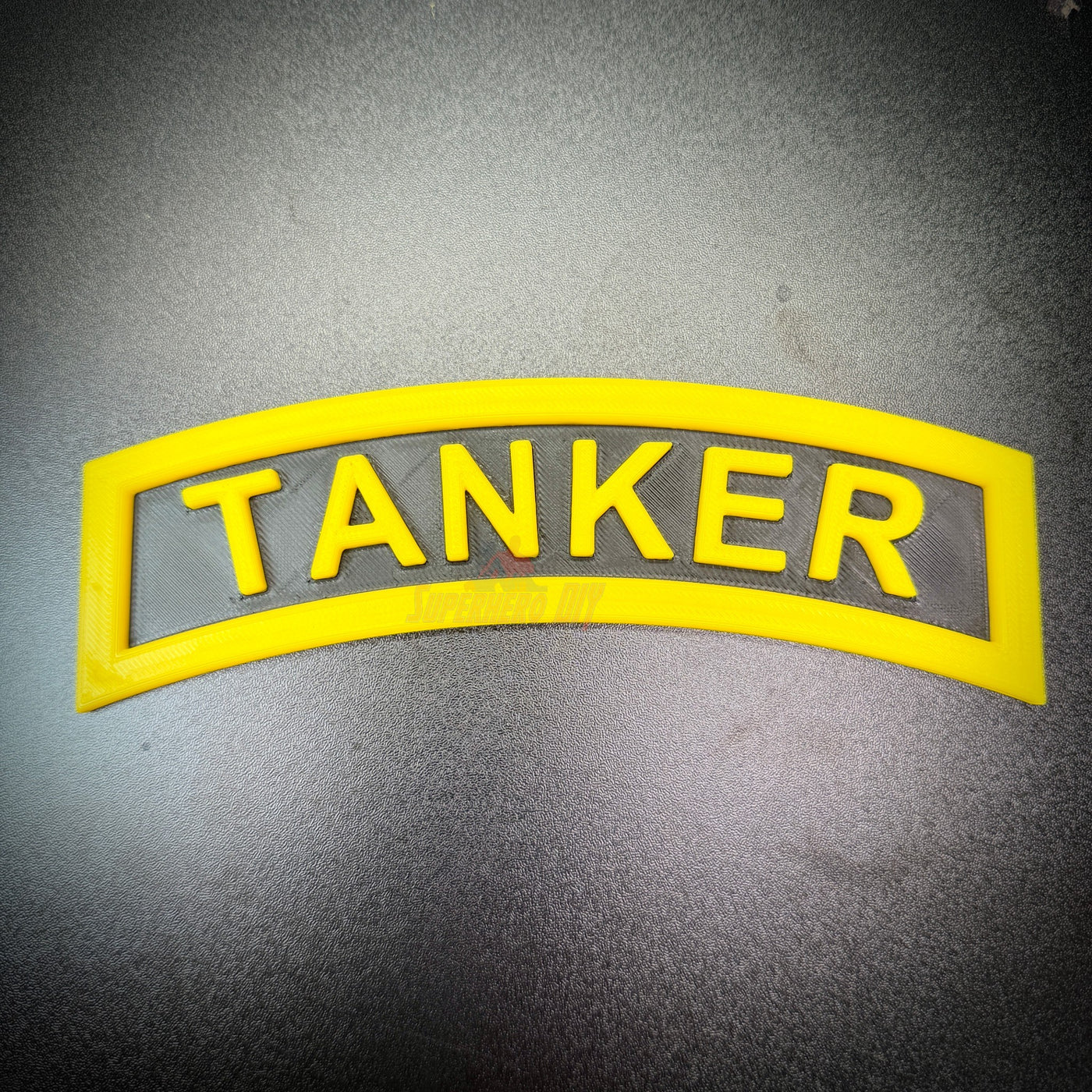 3D tanker tab in raised yellow letters against a black background, designed for military shadow boxes.