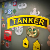 3D tanker tab in yellow and black showcased against military insignia background.