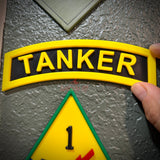 3D tanker tab showcased with raised lettering against a textured background, emphasizing its military design.