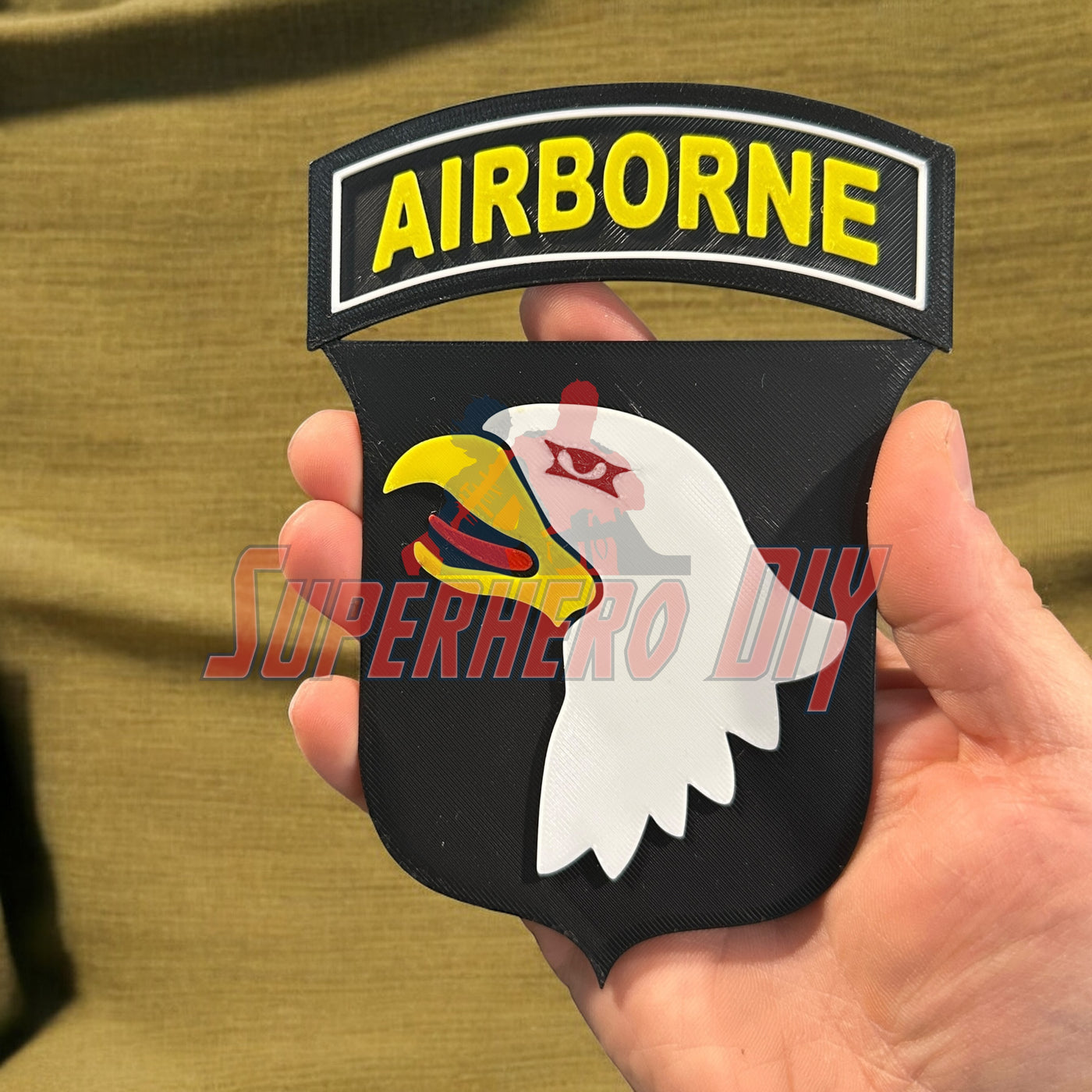 Hand holding 101st Airborne Division display insignia, 3D-printed emblem with eagle design, military honor piece.